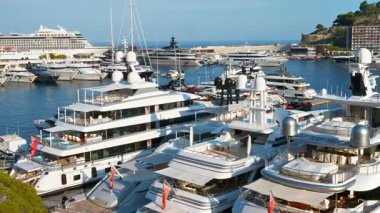Monaco Marina 'ya kenetlenmiş beyaz tekne manzarası. Arka planda şehrin silüeti var.