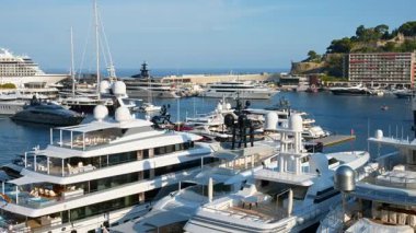 Monaco Marina 'ya kenetlenmiş beyaz tekne manzarası. Arka planda şehrin silüeti var.