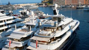 Monaco Marina 'ya kenetlenmiş beyaz tekne manzarası. Arka planda şehrin silüeti var.