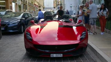 Monte Carlo, Monaco - 4 Ekim 2024: Kırmızı Ferrari sokağa park edilmiş insanlar etrafta dolaşıyordu.