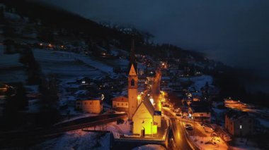 Selva di Cadore, İtalya - 11 Ocak 2025: San Lorenzo Kilisesi 'nin insansız hava aracı görüntüsü Dolomites, İtalya' daki Selva di Cadore komünü tarafından gece aydınlatıldı