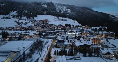 Corvara, Badia, İtalya - 9 Ocak 2025: Kuzey İtalya 'daki Güney Tyrol, Dolomites' te mavi saatte karla kaplı Corvara köyünün insansız hava aracı görüntüsü