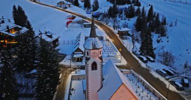 Kuzey İtalya 'daki Güney Tyrol, Dolomitler' de mavi saatte karla kaplı Corvara köyünün insansız hava aracı görüntüsü.