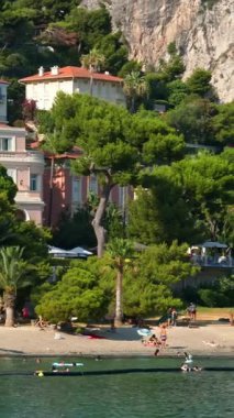 Beaulieu-sur-Mer, Fransa - 5 Temmuz 2024: İnsanlar Petite Afrique Sahili 'nde yüzüyor ve dinleniyorlar. Dikey