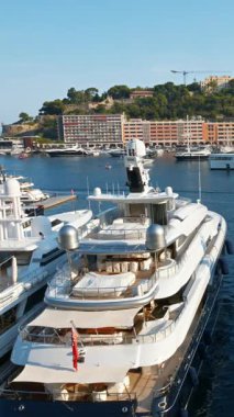 Monaco Marina 'ya kenetlenmiş beyaz tekne manzarası ve arka planda şehrin ufuk çizgisi. Dikey