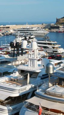 Monaco Marina 'ya kenetlenmiş beyaz tekne manzarası ve arka planda şehrin ufuk çizgisi. Dikey