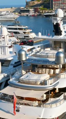 Monaco Marina 'ya kenetlenmiş beyaz tekne manzarası ve arka planda şehrin ufuk çizgisi. Dikey