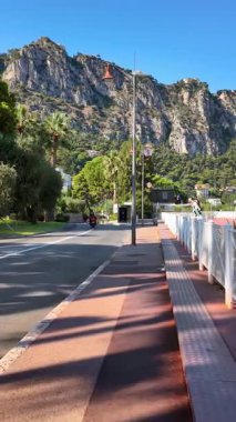 Beaulieu-sur-Mer, Fransa - 5 Temmuz 2024: Arabalar gün ışığında şehrin sokaklarında hareket ediyor. Dikey