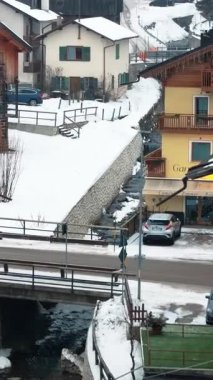 Corvara, Badia, İtalya - 10 Ocak 2025: Dolomitler, Güney Tyrol 'de karla kaplı köydeki evlerin insansız hava aracı görüntüsü. Dikey