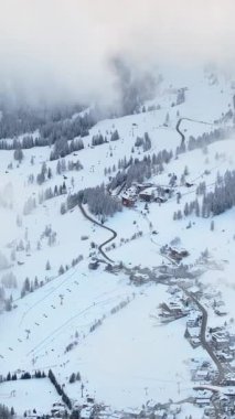 Güney Tyrol, Dolomites, Kuzey İtalya 'da karla kaplı Colfosco dağ köyünün insansız hava aracı görüntüsü. Dikey