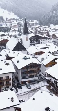 Corvara, İtalya - 9 Ocak 2025: Kuzey İtalya 'daki Güney Tyrol, Dolomites' te karla kaplı Corvara köyünün insansız hava aracı görüntüsü. Dikey