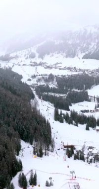 Kuzey İtalya 'daki Güney Tyrol, Dolomitler' de karla kaplı Corvara köyünün insansız hava aracı görüntüsü. Dikey