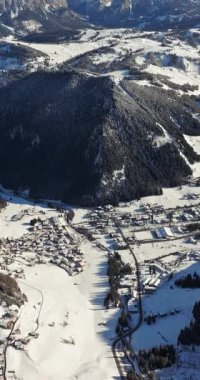Güney Tyrol, Dolomites, Kuzey İtalya 'da karla kaplı Colfosco dağ köyünün insansız hava aracı görüntüsü. Dikey