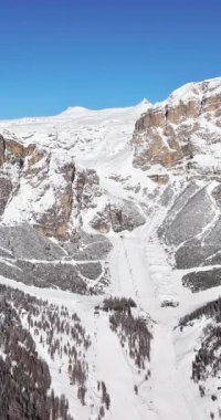 Güney Tyrol, Dolomites, Kuzey İtalya 'daki Colfosco köyünde karla kaplı dağların insansız hava aracı görüntüsü. Dikey
