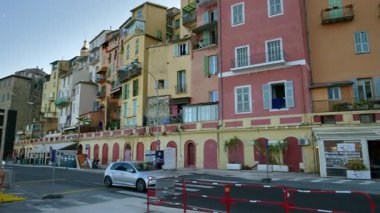 Menton, Fransa - 4 Eylül 2024: Şehirdeki renkli binaların ve kıyı şeridinde yürüyen insanların görüntüsü