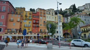 Menton, Fransa - 4 Eylül 2024: Şehirdeki renkli binaların ve kıyı şeridinde yürüyen insanların görüntüsü