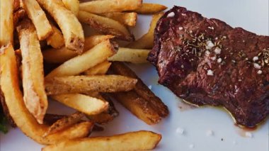 Restoranda beyaz bir tabakta patates kızartması ve salatayla kazığı yakın.