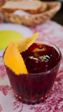 Lokantadaki kırmızı beyaz masa örtüsüne negroni kokteyli koy. Dikey