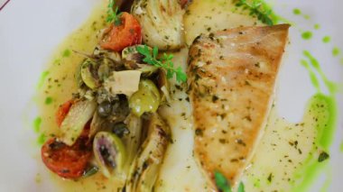 Restoranda beyaz bir tabakta sebzeli ızgara somon balığı yakın.