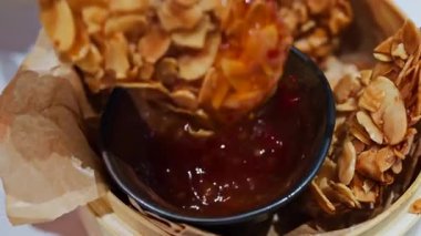 Bir kadının çıtır çıtır, badem kaplamalı kızarmış yiyecekleri kırmızı sosa batırması.