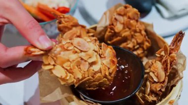 Bir kadının çıtır çıtır, badem kaplamalı kızarmış yiyecekleri kırmızı sosa batırması.