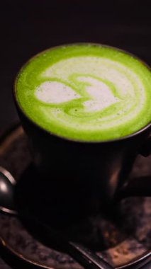 Bir kafede tepside bir matcha latte 'yi yakın çekim. Dikey
