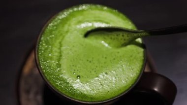 Kafedeki bir tepside, bir kaşığı matcha latte 'ye karıştır.