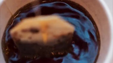 Kırmızı fincanda demlenen çay poşetini kapat.