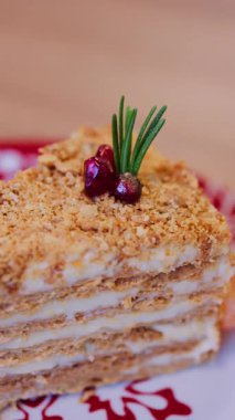 Kırmızı ve beyaz bir tabakta Medovik pastasından bir dilim yakın.