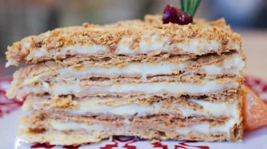 Kırmızı ve beyaz bir tabakta Medovik pastasından bir dilim yakın.