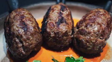 Üç ızgara et şişi portakal soslu bir tabakta servis ediliyor.