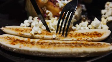 Lokantada siyah bir tabakta muzlu ve karamelli patlamış mısırla cheesecake kesen bir kadına yaklaş.