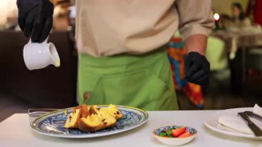 Garson lokantada birden fazla panettone parçasına yoğunlaştırılmış süt döküyor.