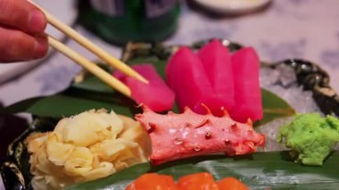 Ton balıklı sashimi 'yi yemek çubuğuyla alıp yiyen bir adama yaklaş.