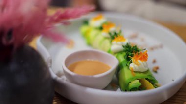 Bir restoranda beyaz bir tabakta soslu avokado rulosunu kapat.