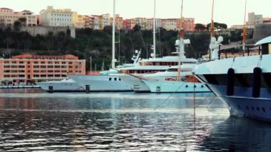 Monaco Marina 'ya kenetlenmiş teknelerin görüntüsü ve arka planda şehrin silüeti.