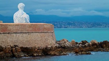 Fransa 'nın Antibes şehrinde akşam saatlerinde Jaume Plensa' nın Göçebe şehir heykelinin uzaktan görünüşü