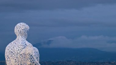 Fransa 'nın Antibes şehrinde akşam saatlerinde Jaume Plensa' nın Göçebe şehir heykelinin uzaktan görünüşü