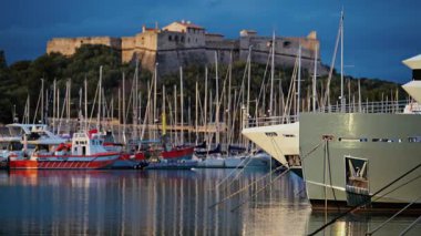Fransa 'nın Antibes şehrinde günbatımında arka planda Fort Carre ile Vauban Limanı' na yanaşan tekneler.