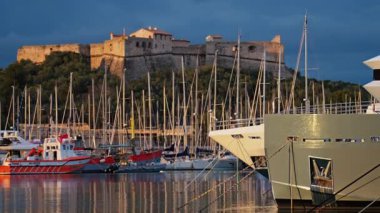 Fransa 'nın Antibes şehrinde günbatımında arka planda Fort Carre ile Vauban Limanı' na yanaşan tekneler.