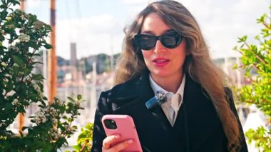 Fransa 'nın Cannes kentindeki Pierre Canto Limanı' na demirlemiş, teknelerin önünde konuşan güneş gözlüklü bir kadın.