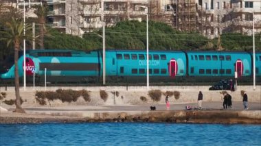 Juan-les-Pins, Fransa - 25 Ocak 2025: Antibes 'te deniz kıyısındaki raylarda ilerleyen mavi tren