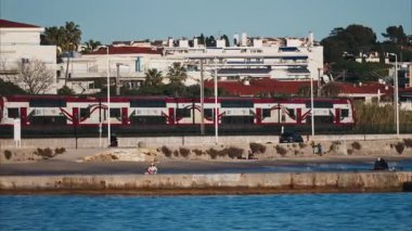 Juan-les-Pins, Fransa - 25 Ocak 2025: Antibes 'te deniz kıyısındaki raylarda ilerleyen kırmızı tren
