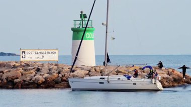 Antibes, Fransa - 14 Şubat 2025: Deniz feneri yakınlarında bulutlu bir günde Fransa bayrağıyla denizde hareket eden tekne