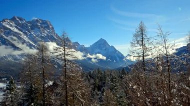 Arkadaki bulutlu gökyüzü ile Dolomitler, İtalya 'daki ağaçların ve dağların üzerindeki kar manzarası