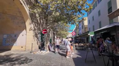 Antibes, Fransa - 13 Ağustos 2024: Şehrin sokaklarındaki açık kafelerin yakınında yürüyen insanlar