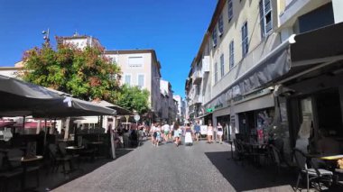 Antibes, Fransa - 13 Ağustos 2024: Şehrin sokaklarındaki açık kafelerin yakınında yürüyen insanlar