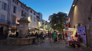 Antibes, Fransa - 13 Ağustos 2024: İnsanlar akşam saatlerinde kentin sokaklarındaki açık kafelerin yakınında yürüyorlar