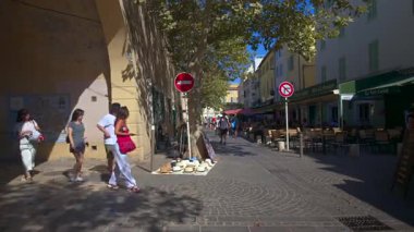 Antibes, Fransa - 13 Ağustos 2024: Şehrin sokaklarındaki açık kafelerin yakınında yürüyen insanlar