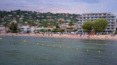 Golfe Juan, Fransa - 14 Ağustos 2024: İnsanlar gün batımında bulutlu bir günde Golfe-Juan kasabasında plajda dinleniyor